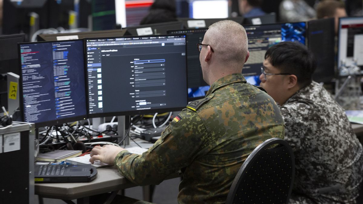 Soldaten aus Deutschland und Singapur arbeiten während einer Cybersicherheitsübung der NATO zusammen. Zwei Soldaten sitzen vor einem Computer.