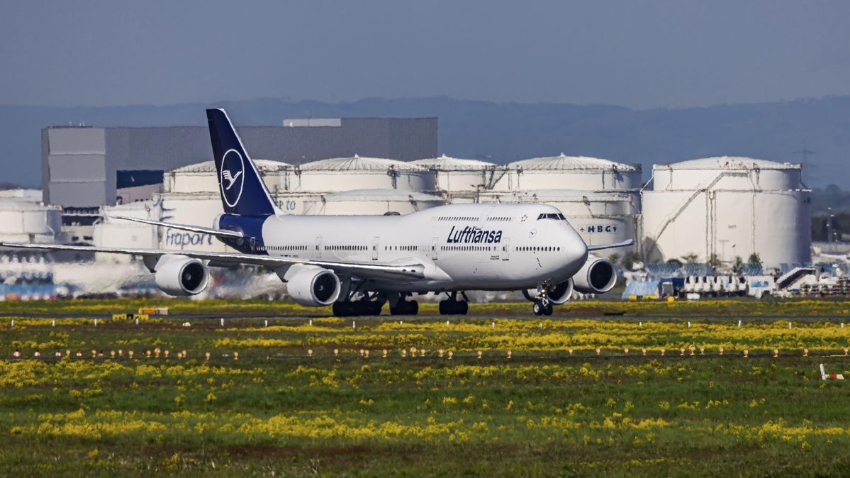 Jumbo-Jet am Flughafen Fraport in Frankfurt vor einem Tanklager für Flugbenzin Ein Passagierflugzeug auf dem Rollfeld eines Flughafens vor großen Kerosintanks