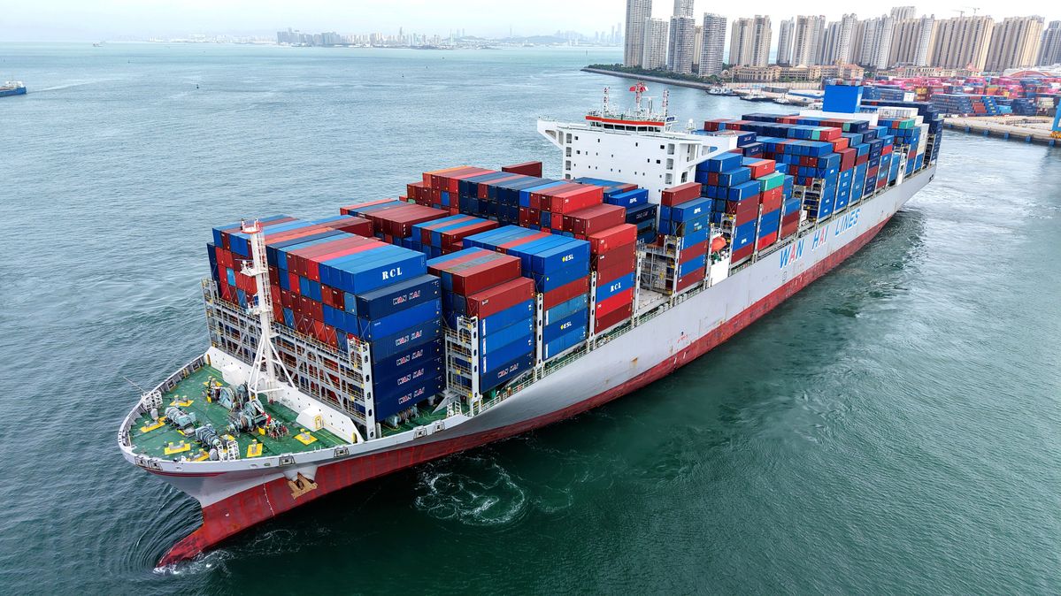 A cargo ship with containers in front of a city skyline