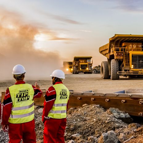 Large Dump Trucks transporting Platinum ore for processing with mining safety inspectors in the foreground