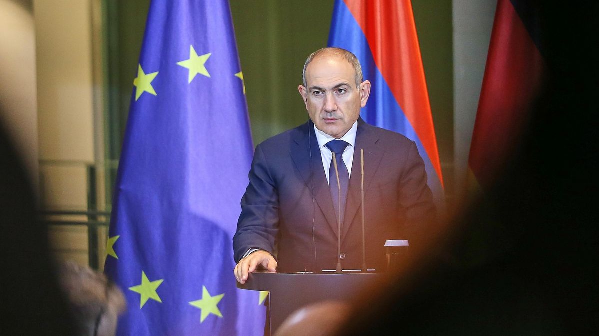 Der Ministerpräsident an einem Pult vor einer EU und einer armenischen Flagge 