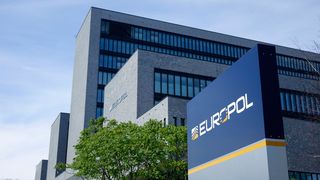 Ein Schild mit der Aufschrift „EUROPOL“ steht vor einem grauen Bürogebäude.