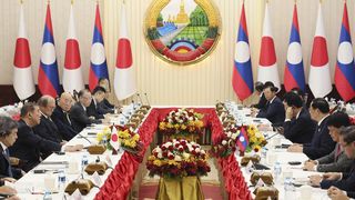 Political representatives from Japan and Laos sit opposite each other in a room