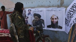 Taliban fighter looks at Taliban flags and posters of leaders in Kabul, Afghanistan