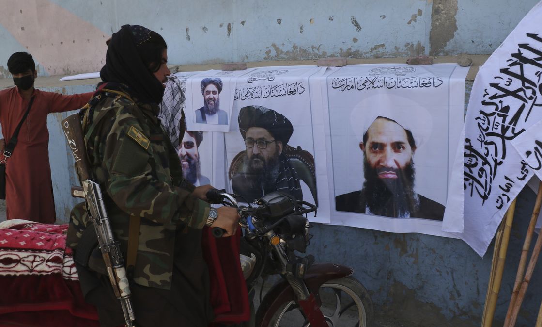 Taliban fighter looks at Taliban flags and posters of leaders in Kabul, Afghanistan
