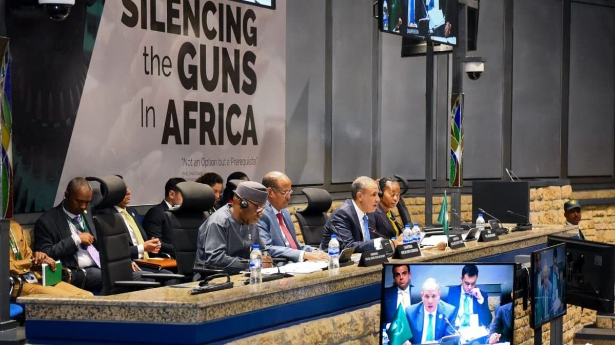 Mehrere Männer an einem Tisch, dahinter der Schriftzug "Silencing the Guns in Africa"