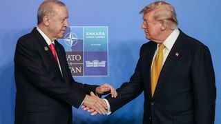 Der türkische und der amerikanische Präsident geben sich die Hand vor einem Nato Banner.