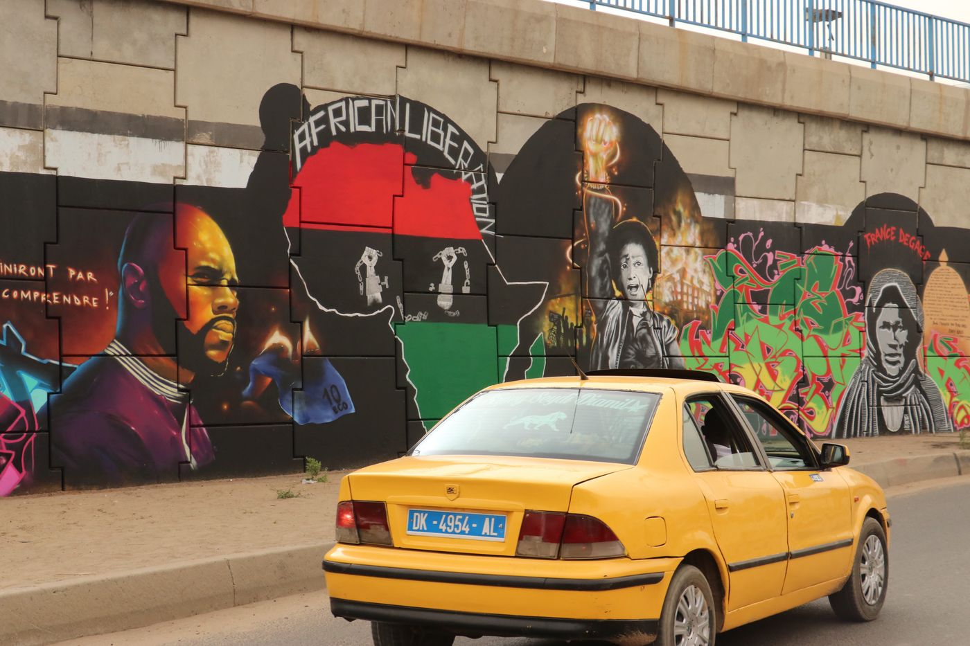 Juni 2020, Dakar, Senegal: Ein Auto fährt an einem Wandgemälde des Graffitikünstler-Kollektivs „RBS Crew“ vorbei. Darauf zu sehen ist der Anti-CFA-Aktivist Kémi Séba. 