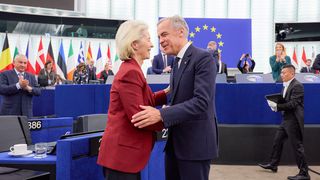 Von der Leyer und Carney geben sich in einem Sitzungssaal mit Europaflagge die Hand.