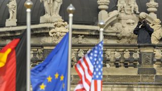 Ein Beamter mit Fernglas hinter drei Flaggen