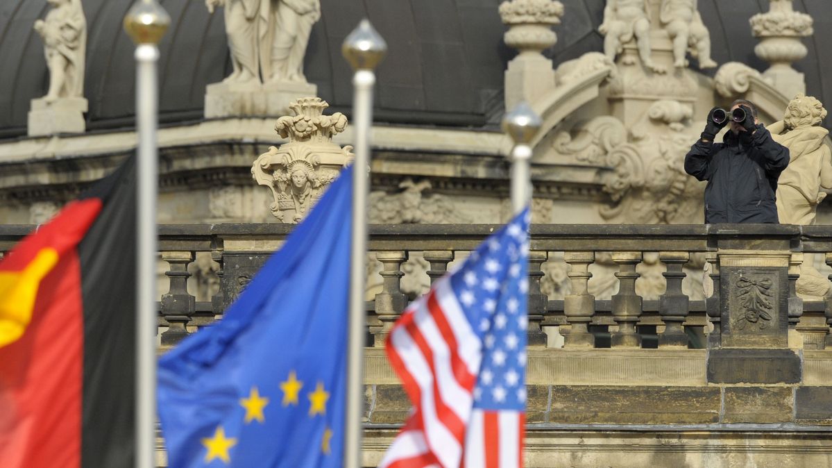 Ein Beamter mit Fernglas hinter drei Flaggen