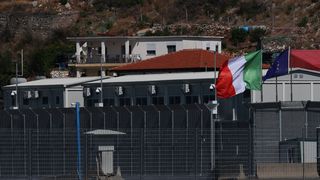Houses behind a high fence with an Italian flag