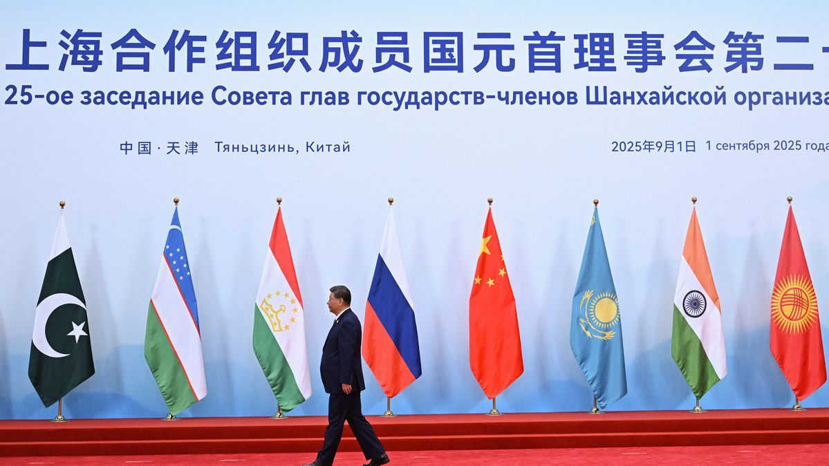 Präsident von China läuft vor Wand mit Flaggen.