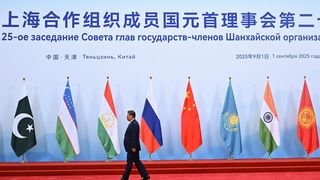 Präsident von China läuft vor Wand mit Flaggen.