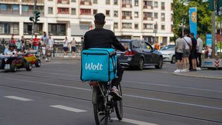 Ein Fahrradfahrer mit großer Tasche steht an einer Kreuzung.