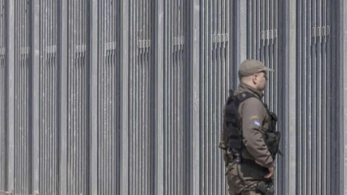 Ein Polizist in Uniform vor einem hohen Grenzzaun