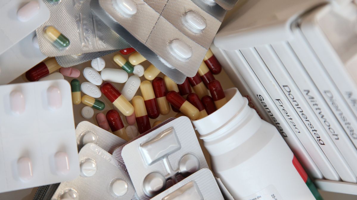 Tabletten liegen lose übereinander, daneben ein Stapel mit Medikamentenpackungen