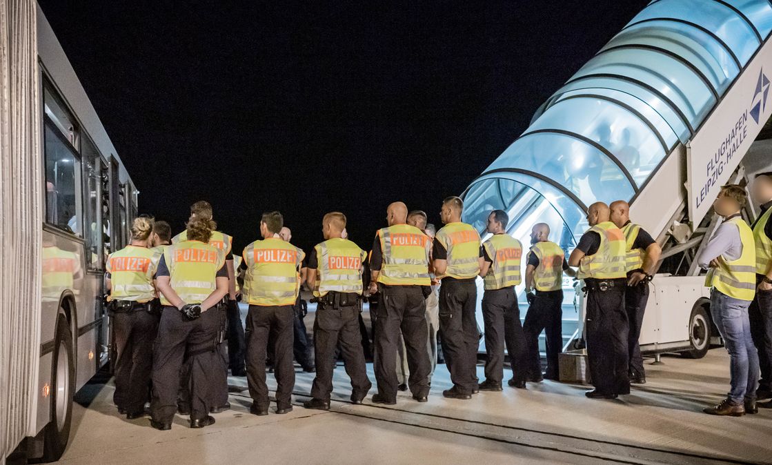 Polizeibeamte begleiten einen Afghanen auf dem Flughafen Leipzig-Halle in ein Charterflugzeug