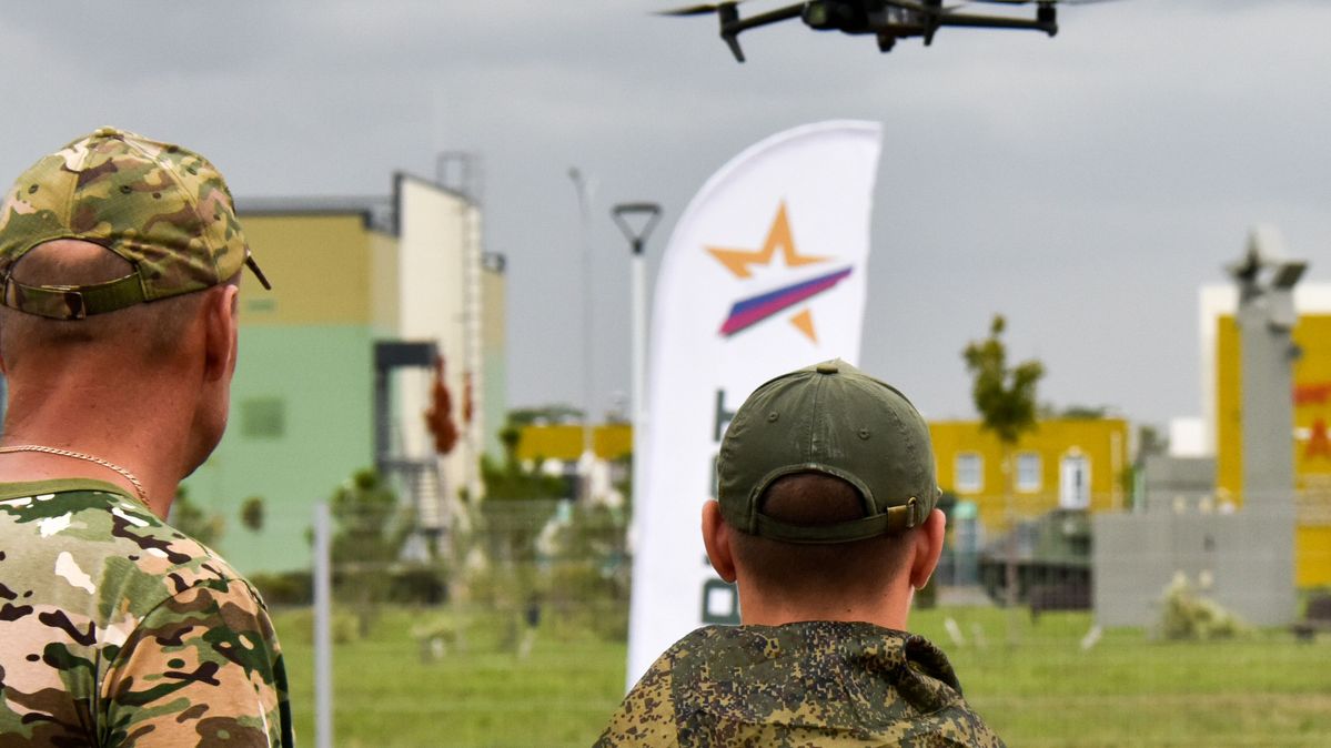 Two soldiers look at a flying quadcopter.