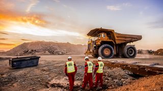 Large dump trucks transporting platinum ore for processing, with mining safety inspectors in the foreground.