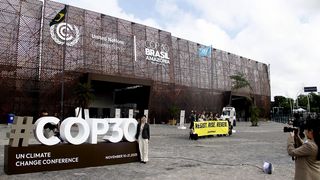 Eine Gruppe Greenpeace-Aktivisten steht mit einem Banner vor dem Veranstaltungsort des UN-Klimagipfels COP30 in Brasilien