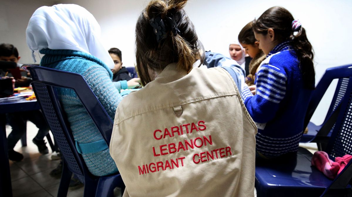 Eine Person, die eine Jacke mit der Aufschrift »Caritas Lebanon Migrant Center« trägt, leitet eine Gruppe von Kindern an.