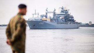 Ein Marinesoldat steht vor einem militärischen Versorgungsschiff.