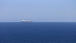 Ein Traktor fährt über ein grünes Feld mit einer Spritzmaschine.