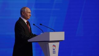 Der russische Präsident steht an einem Redepult vor einer blauen Wand.