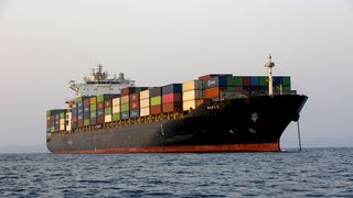 Ein mit Containern beladenes Schiff ankert im Meer