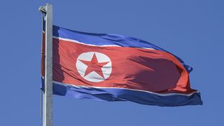 Die nordkoreanische Fahne an einem Mast vor blauem Himmel