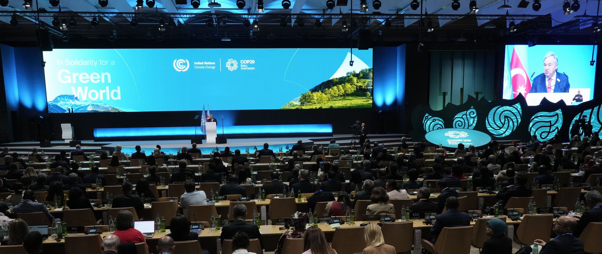 People sit in front of a large stage where a man is speaking.
