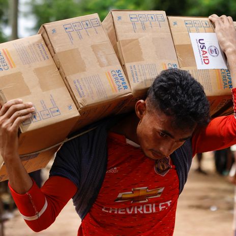 Ein Rohingya-Mann trägt Pakete mit Hilfslieferungen von USAID zu einem Warenhaus in einem Flüchtlingslager in Bangladesch.